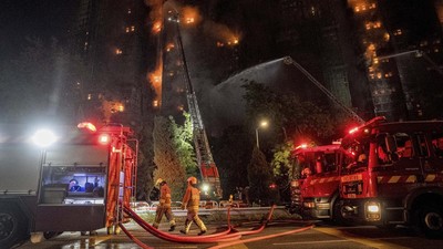Petugas-pemadam-kebakaran-menyemprotkan-air-ke-kompleks-apartemen-Wang-Fuk-Court-di-Tai-Po-Hong-Kong-yang-diselimuti-perancah-bambu-yang-terbakar.